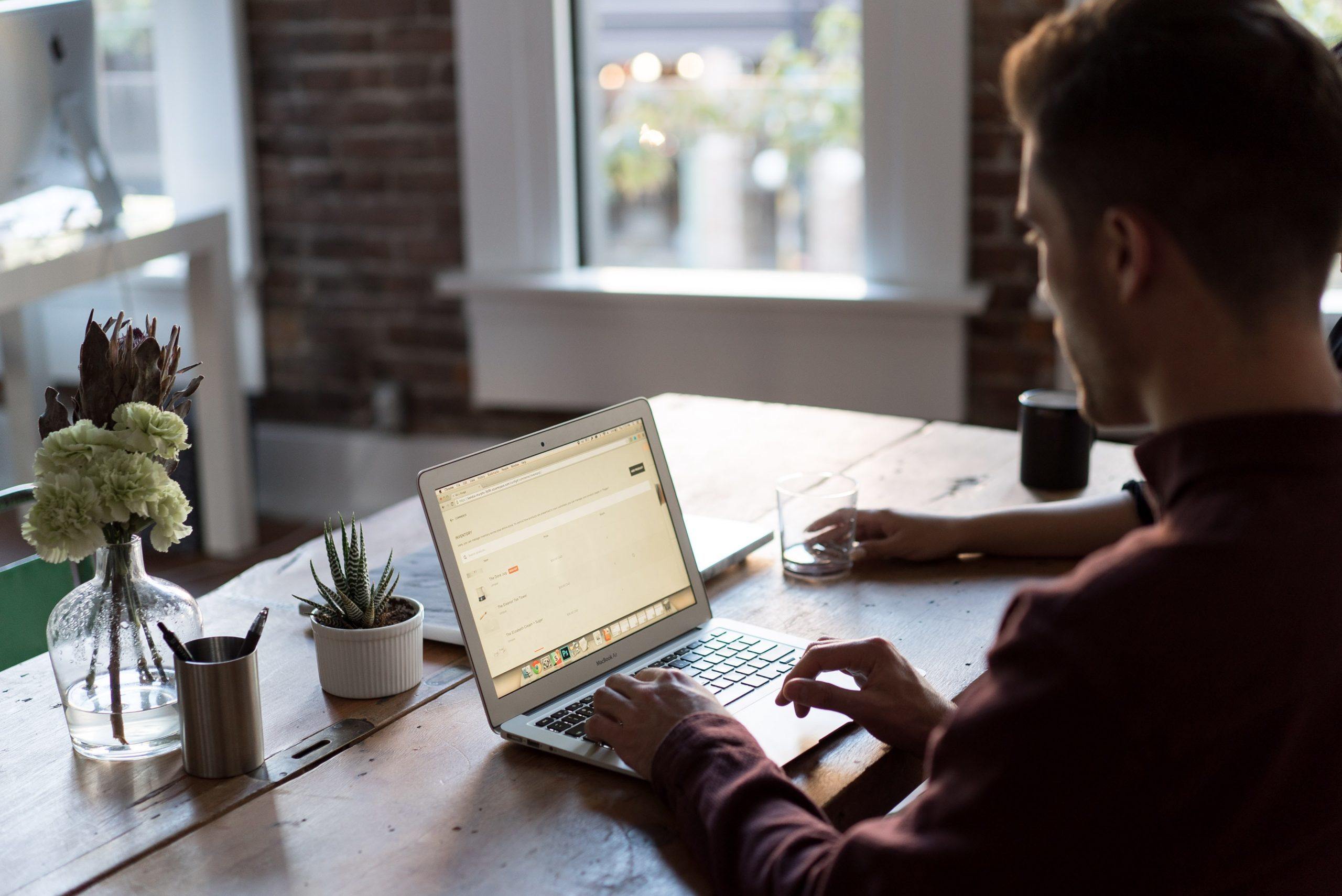 man sitting at desk doing work on a laptop