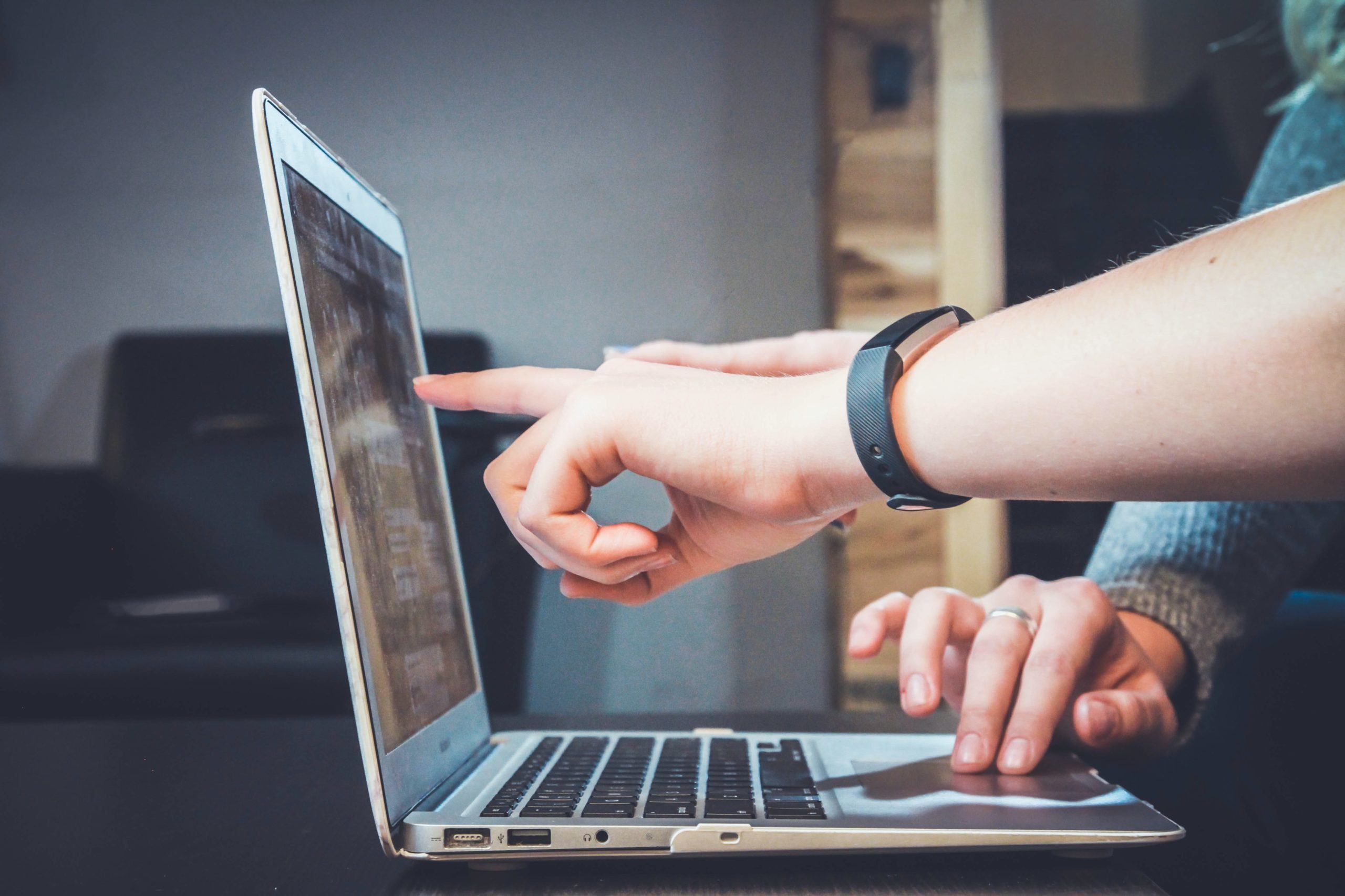 Fingers pointing at a computer screen 